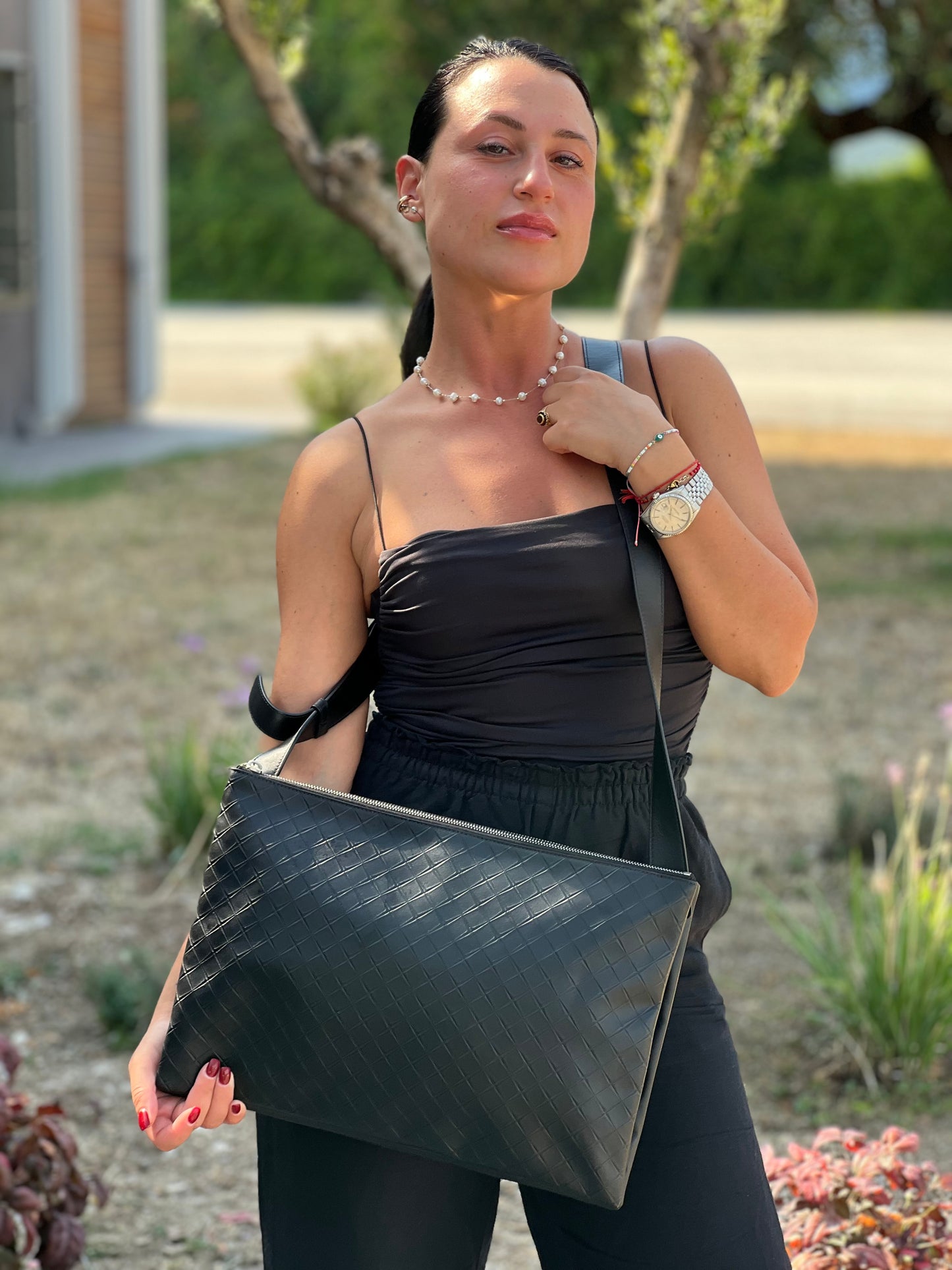 Cartella Bottega Veneta in pelle intrecciata nera, rifinita con inserti metallici argentati e munita di una tracolla regolabile