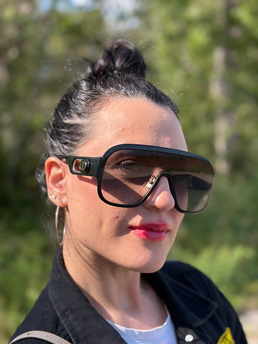 Ragazza che indossa un paio di occhiali da sole Dior in acetato nero, usati, originali, second hand, in ottime condizioni.