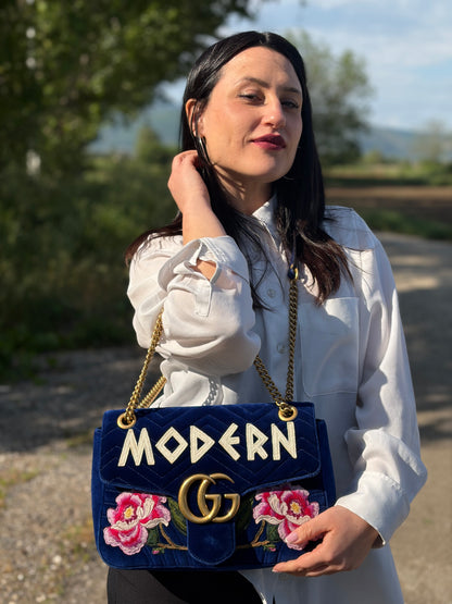 Ragazza che indossa una borsa Gucci Marmont nella misura grande velvet color blu reale, con patchwork decorativi, usata, originale, second hand, in ottime condizioni.