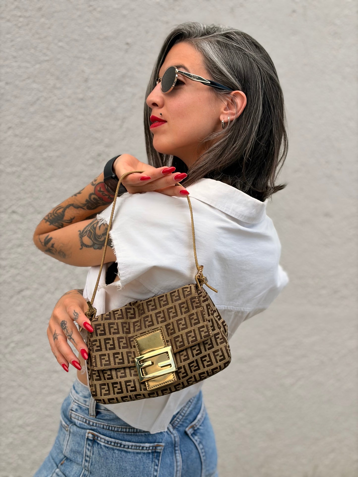 Ragazza che indossa una borsa a spalla Fendi in tessuto beige e marrone trama Zucchino, con finiture in pelle dorate, usata, originale, second hand, in ottime condizioni.