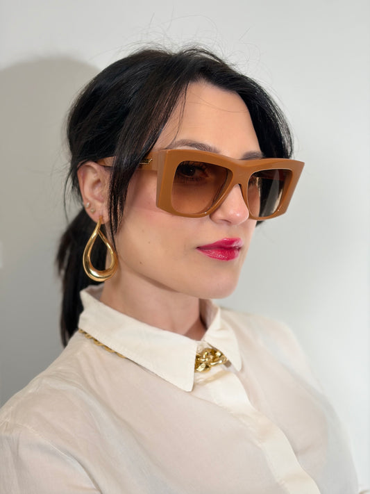 Ragazza che indossa degli occhiali da sole strutturati di Bottega Veneta color caramello e con lenti sfumate, usati, originali, second hand, in ottime condizioni.