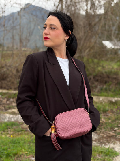 Ragazza che indossa una tracolla Gucci Microguccissima in color rosa metallizzato, con nappa decorativa con dettaglio bambù