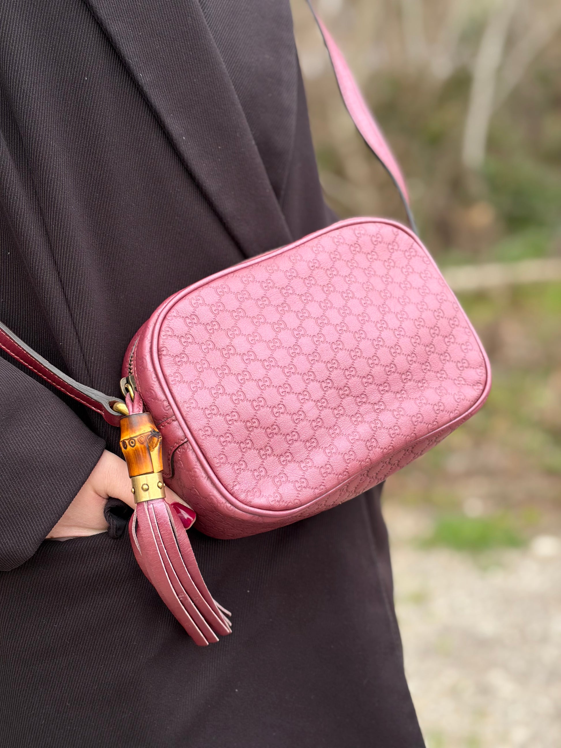 Ragazza che indossa una tracolla Gucci Microguccissima in color rosa metallizzato, con nappa decorativa con dettaglio bambù.