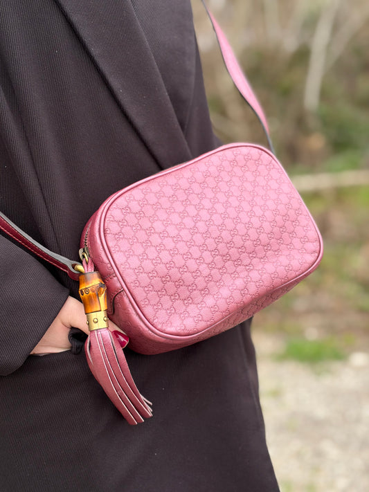 Ragazza che indossa una tracolla Gucci Microguccissima in color rosa metallizzato, con nappa decorativa con dettaglio bambù.