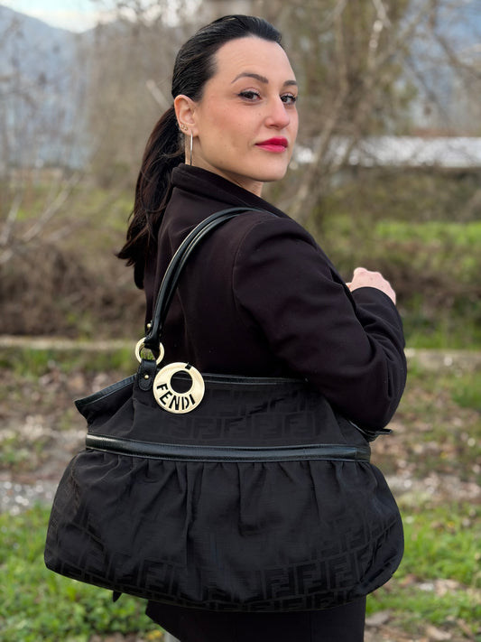 Ragazza che indossa una borsa a spalla Fendi Chef in tessuto trama Zucca nero e metalleria oro chiaro, usata, originale, second hand, in ottime condizioni.