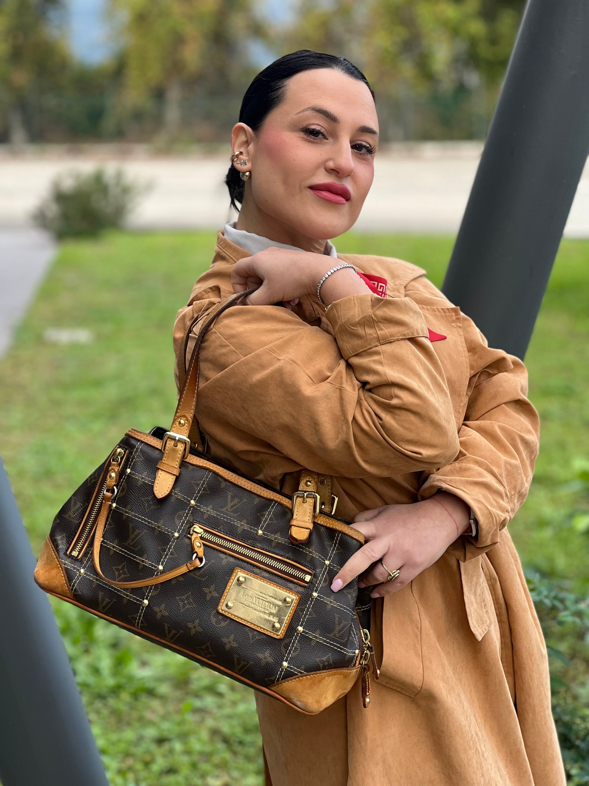 Ragazza che indossa una Borsa Louis Vuitton in canvas marrone monogram con cuciture decorative e finiture in vacchetta naturale. Parti metalliche dorate; munita di doppi manici, indossabile a spalla. Originale, usata, di lusso in ottime condizioni