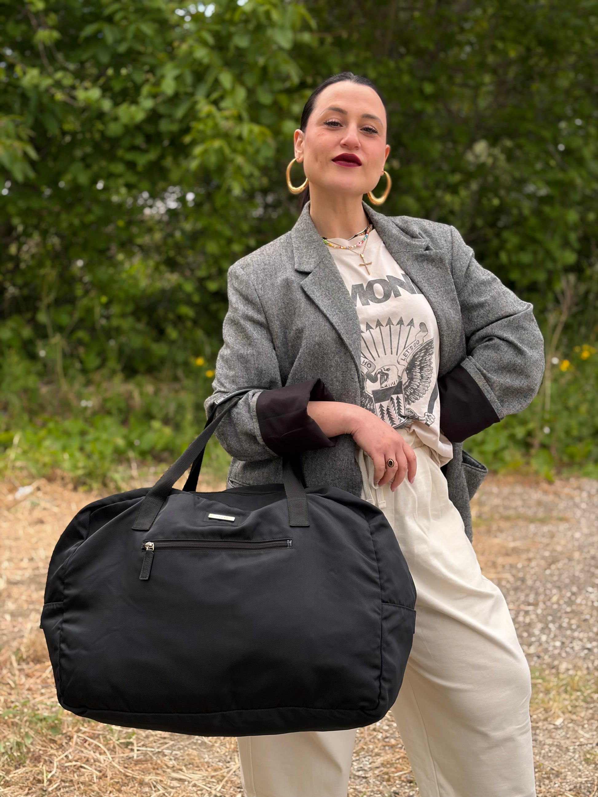 Ragazza che indossa un borsone Gucci in tela nera, con dettagli in pelle tono su tono, usato, originale, second hand, in ottime condizioni.