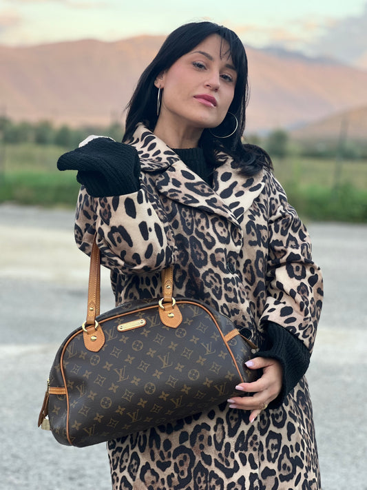 Ragazza che indossa una borsa Louis Vuitton in canvas marrone monogram con finiture in vacchetta naturale e parti metalliche dorate; munita di doppi manici, da portare a spalla. Completa di dustbag e lucchetto. Indossabile a mano.