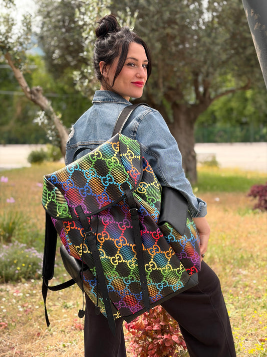 Ragazza che indossa un maxi zaino Gucci in tela e pelle nera, dalla colorata tra GG Supreme, usato, originale, second hand, in condizioni eccellenti.