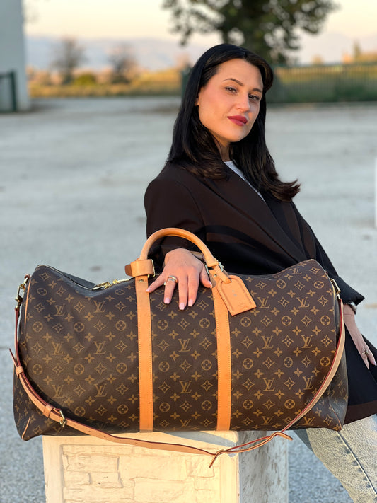 Ragazza che indossa un borsone da viaggio LV in canvas monogram con finiture in vacchetta naturale, munito di una tracolla regolabile e amovibile con spallaccio. Completo di dustbag, lucchetto e chiavi, tag porta address e poignet.