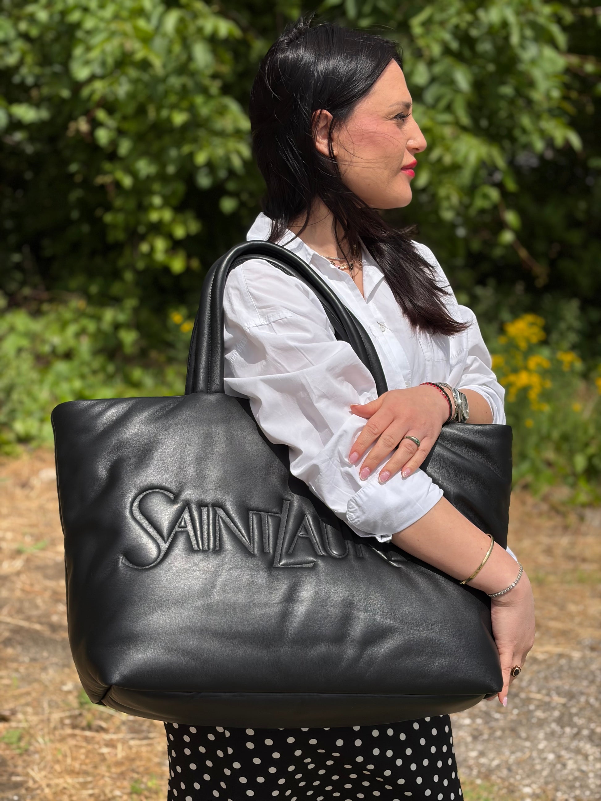 Ragazza che indossa una borsa Saint Laurent in pelle imbottita nera con logo in rilievo Saint Laurent sul front, usata, originale, second hand, in condizioni eccellenti.