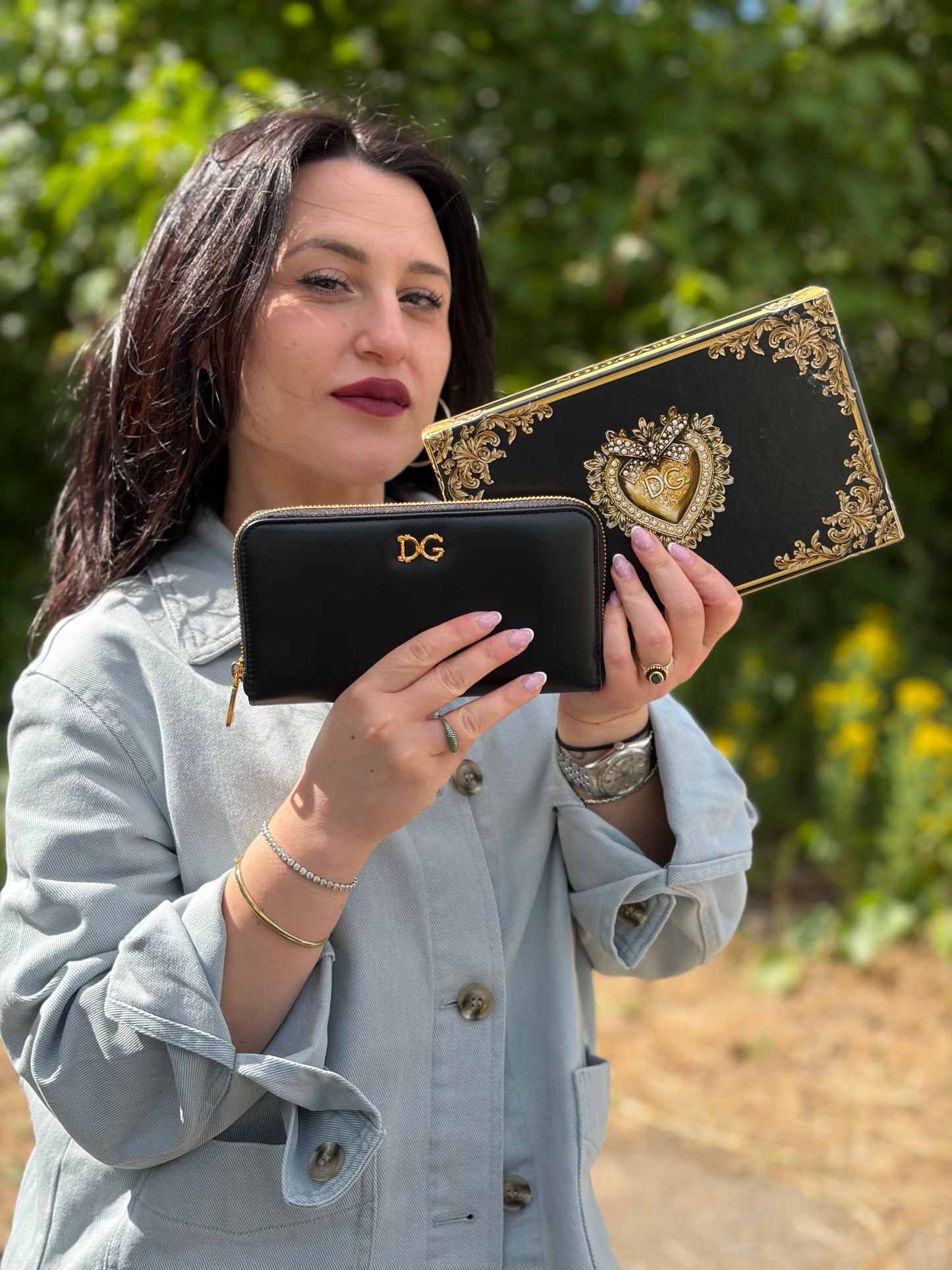 Ragazza che indossa un portafoglio D&G in morbida pelle nera, con logo gioiello sul front, completo di corredo, usato, originale, second hand, in condizioni eccellenti.
