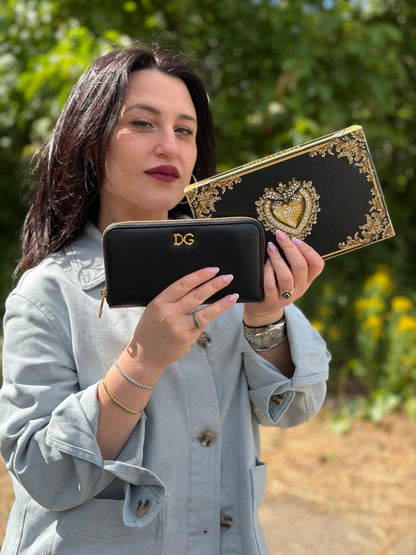 Ragazza che indossa un portafoglio D&G in morbida pelle nera, con logo gioiello sul front, completo di corredo, usato, originale, second hand, in condizioni eccellenti.