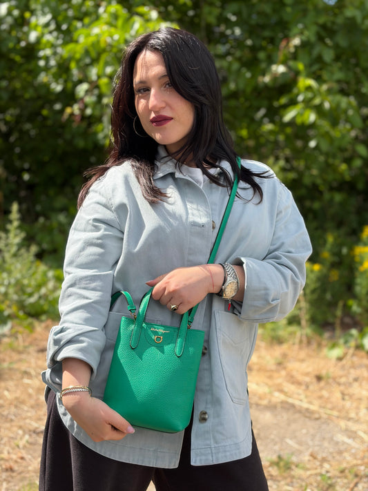 Indossata, Borsa Salvatore Ferragamo in pelle martellata verde smeraldo, presenta l'iconico dettaglio a placca Gancini color oro sul davanti. Indossabile a mano o a tracolla. Originale, usata, di lusso, in condizioni eccellenti.