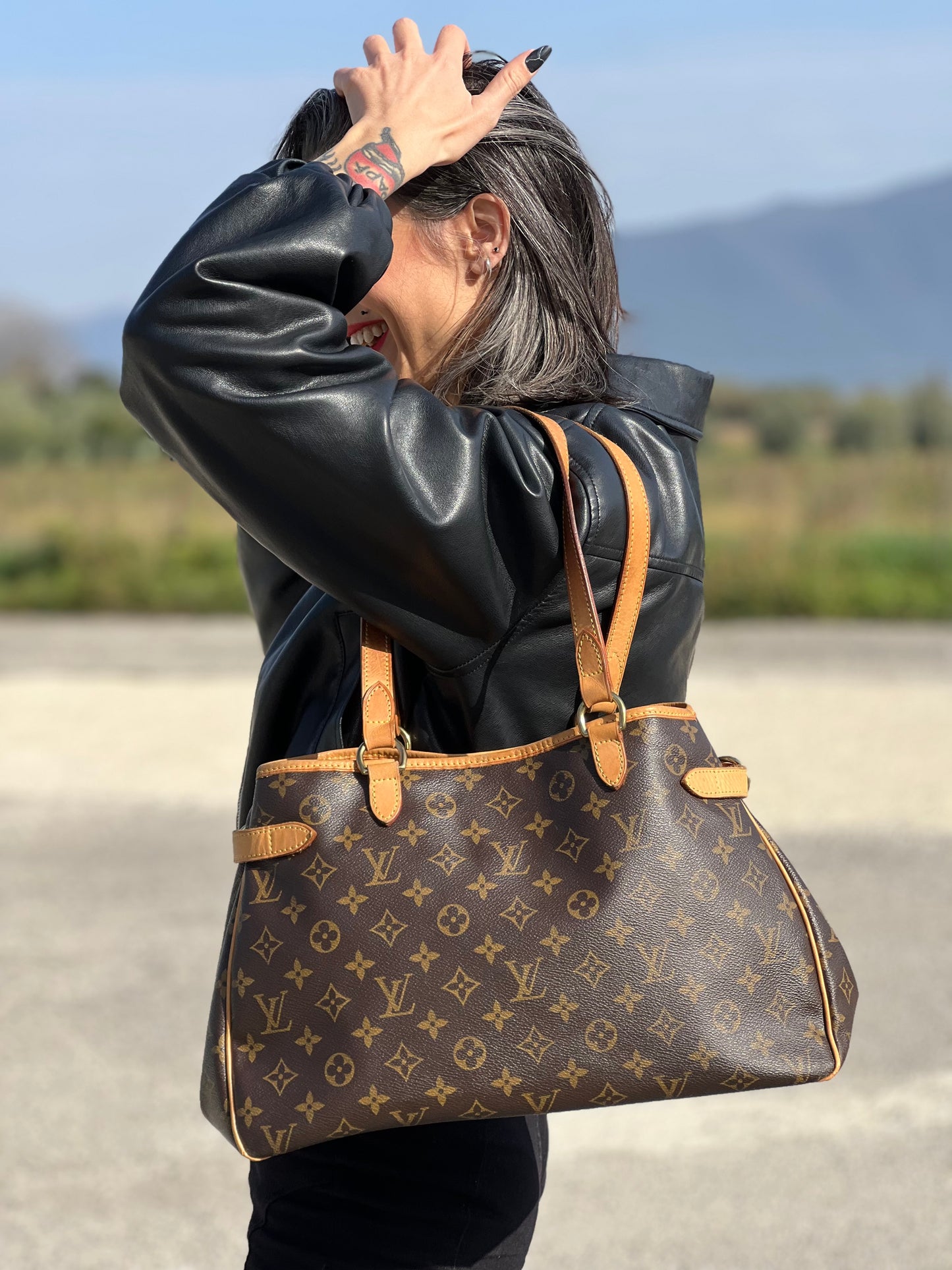 Ragazza che indossa una borsa LV in canvas marrone monogram con finiture in vacchetta naturale e dettagli metallici dorati. Dotata di dustbag.