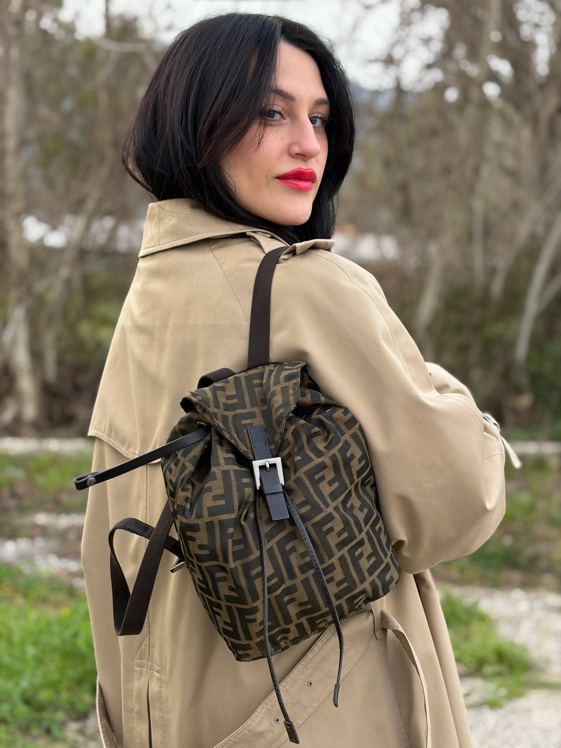Ragazza che indossa uno zaino Fendi in trama Zucca, nelle tonalità del marrone e tabacco, usato, originale, second hand, in ottime condizioni.