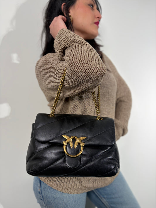 Ragazza che indossa una Pinko in pelle nera trapuntata, indossabile a spalla o a tracolla, usata, originale, second hand, in ottime condizioni.