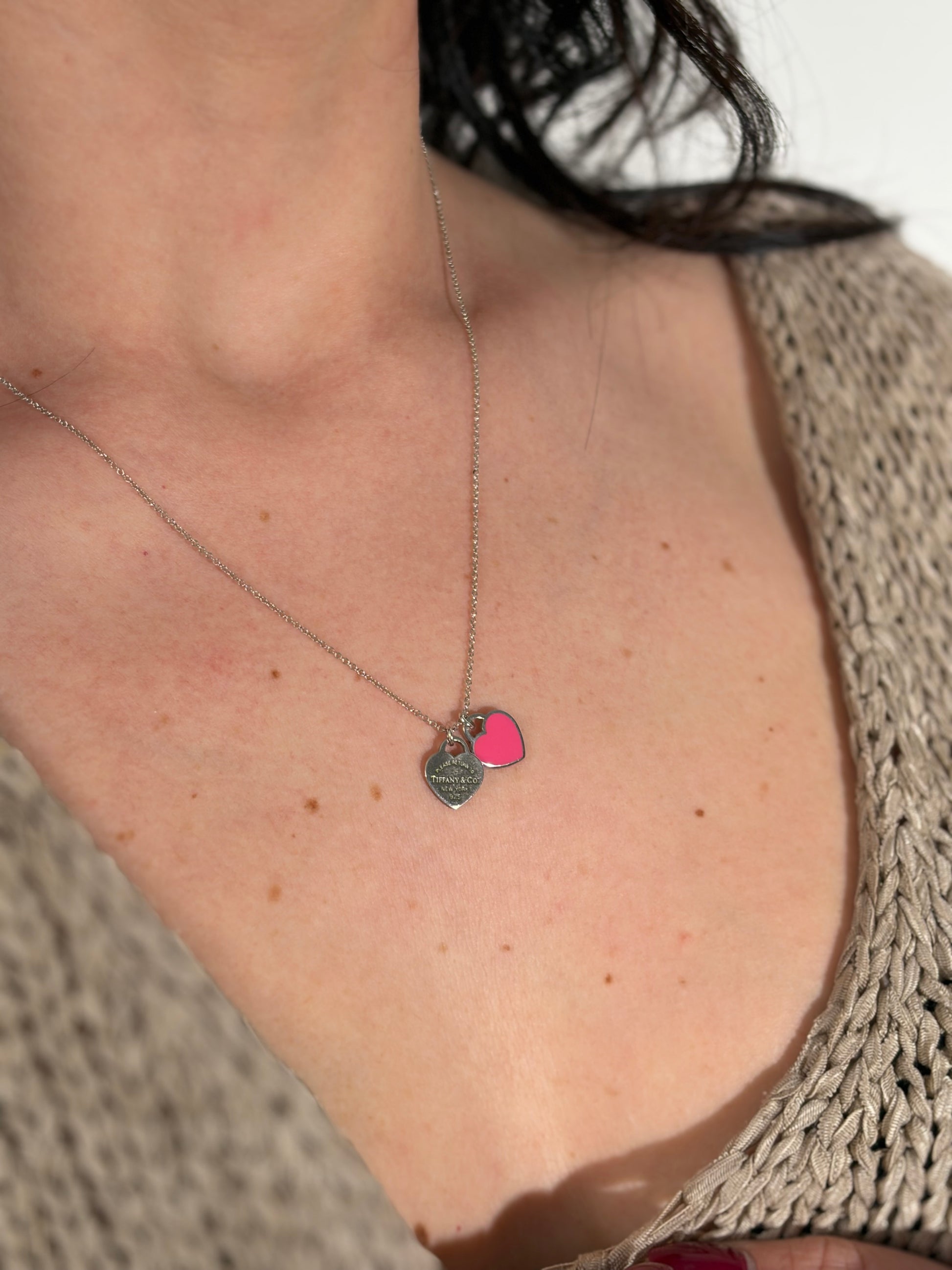 Ragazza che indossa una collana Tiffany&Co. della collezione Return To Tiffany in argento 925 con 2 pendenti heart: uno argentato e l'altro fucsia, originale, usata, second hand, in ottime condizioni.