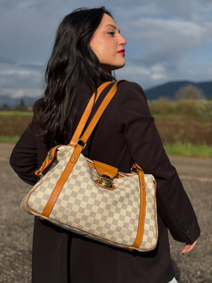 Ragazza che indossa una borsa Louis Vuitton Stresa realizzata in tela Damier Azur con hardware dorato, usata, originale, second hand, in ottime condizioni.