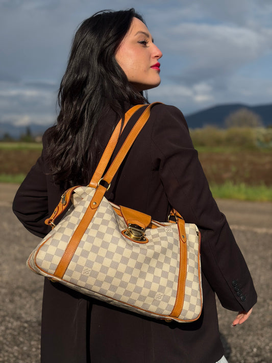 Ragazza che indossa una borsa Louis Vuitton Stresa realizzata in tela Damier Azur con hardware dorato, usata, originale, second hand, in ottime condizioni.