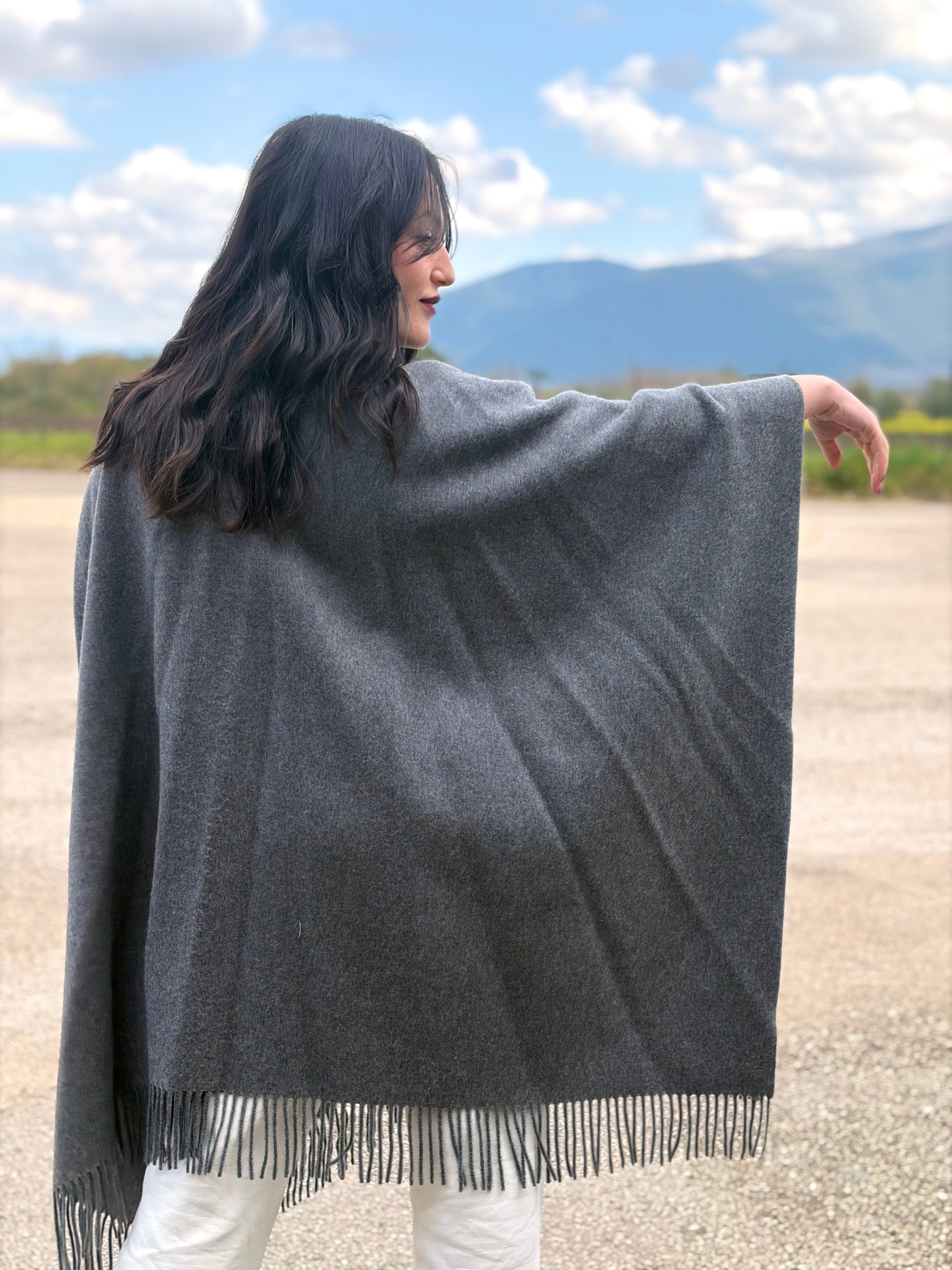 Ragazza che indossa un poncho Herno in morbida lana grigia con tasconi in pelliccia e bordi sfrangiati, usato, originale, second hand, in ottime condizioni.