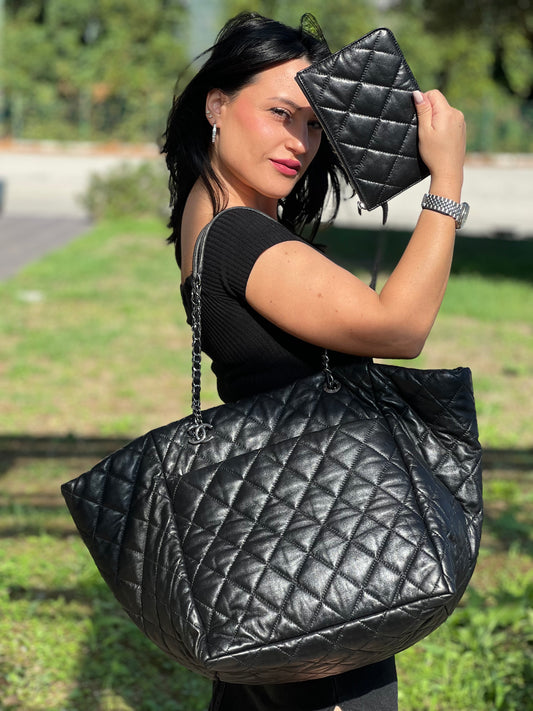Ragazza che indossa una borsa tote Chanel Week End On Mars in pelle matelassé nera, con pochette interna e rifinita con parti metalliche argentate.