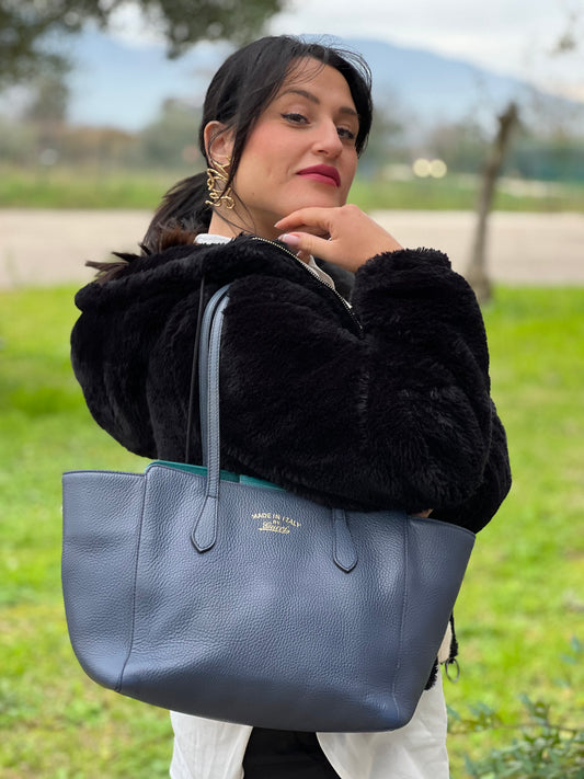 Ragazza che indossa una borsa Gucci in pelle martellata blu scuro, rifinita con inserti metallici dorati; dotata di doppi manici. Indossabile a spalla. Munita di dustbag.