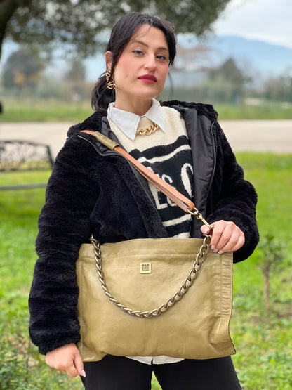 Ragazza che indossa una borsa A.S. 98 in pelle color oliva, dotata di tracolla regolabile in pelle e catena metallica dorata. Presenta chiusura con zip, tasche interne e fodera stampata. Munita di dustbag.