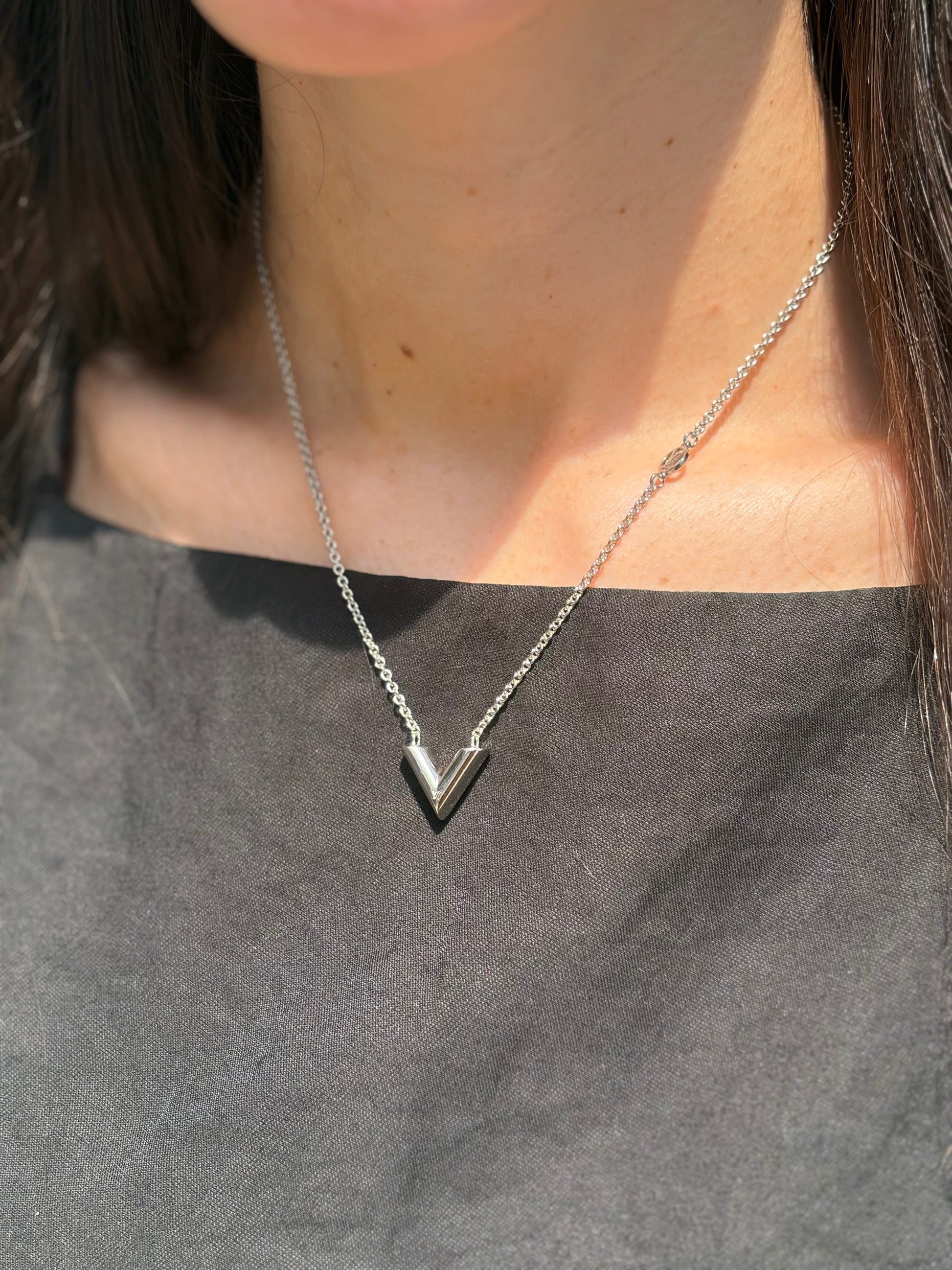Foto indossata Collana Essential V Supple Louis Vuitton in metallo con finitura argentata lucida, impreziosita dal ciondolo con l'emblematica iniziale della Maison. Completata dall'iconico logo LV Circle, che impreziosisce la catenella e la chiusura con moschettone. Originale, di lusso, usata, in condizioni ottime. 