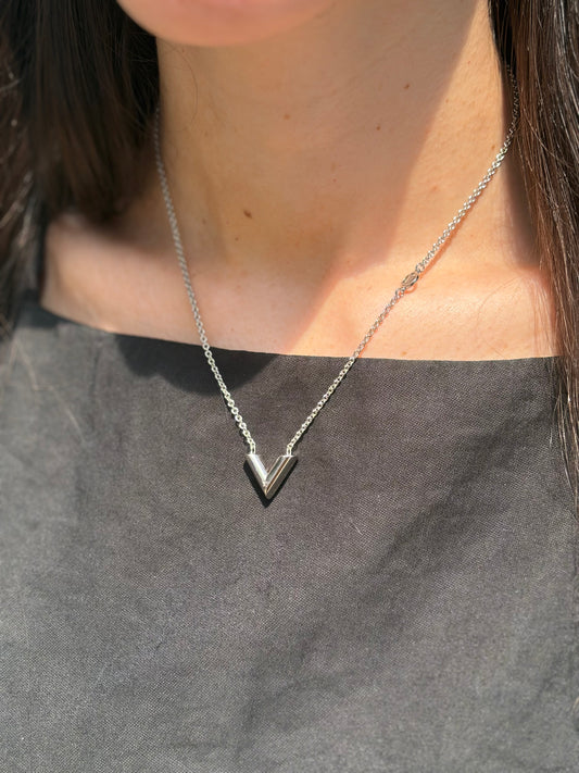 Foto indossata Collana Essential V Supple Louis Vuitton in metallo con finitura argentata lucida, impreziosita dal ciondolo con l'emblematica iniziale della Maison. Completata dall'iconico logo LV Circle, che impreziosisce la catenella e la chiusura con moschettone. Originale, di lusso, usata, in condizioni ottime. 
