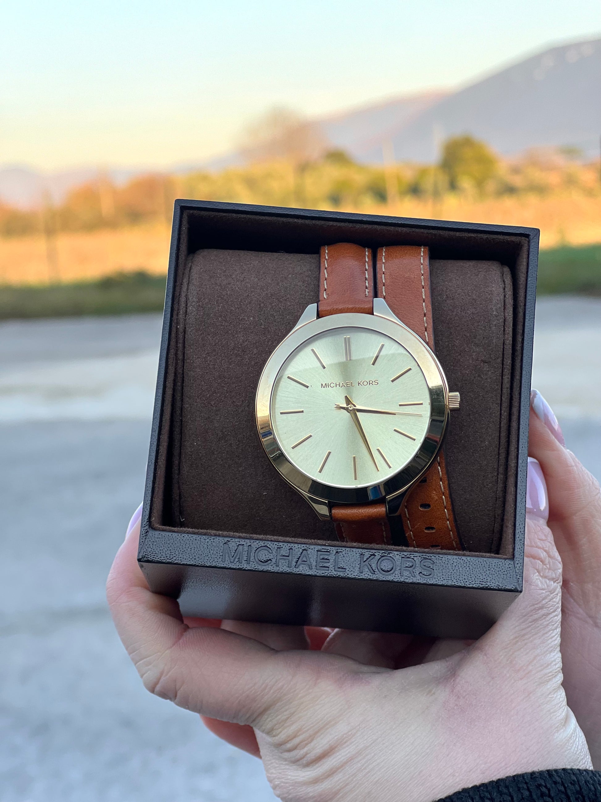 Orologio Michael Kors con cassa dorata e quadrante oro, dotato di cinturino in pelle color caramello a doppio giro, movimento al quarzo, cassa in acciaio inox con impermeabilità 5 ATM, quadrante analogico con indici a barre e lancette ore-minuti-secondi, chiusura ad ardiglione inciso Michael Kors, fondello in acciaio con riferimenti al modello MK-2256 e codice seriale, fornito con scatola ed etichetta.