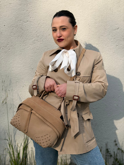 Ragazza che indossa una borsa con tracolla Tod's in pelle scamosciata beige, usata, originale, second hand, in ottime condizioni.