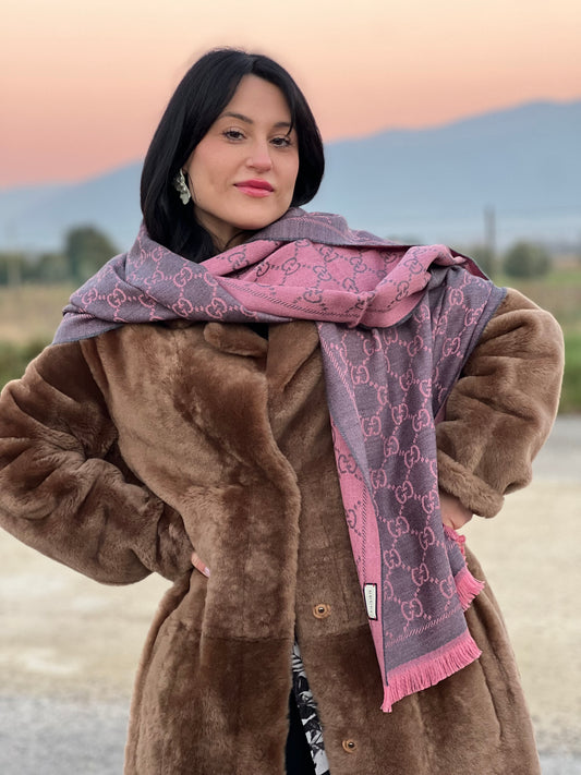 Ragazza che mostra una sciarpa Gucci reversibile in 100% lana rosa e grigia, con trama GG e sfrangiature sui bordi. Munita di cartellino.