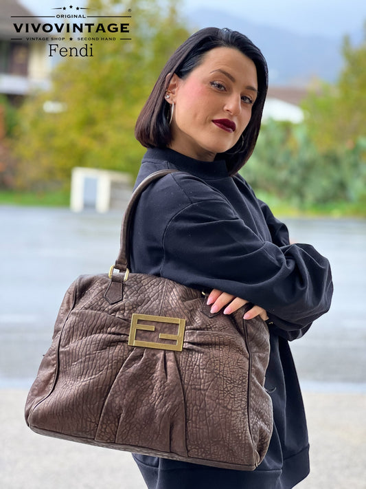 Scopri la shopper Fendi in pelle bronzo con l'iconico logo in metallo dorato. Eleganza e stile in un design spazioso e versatile.