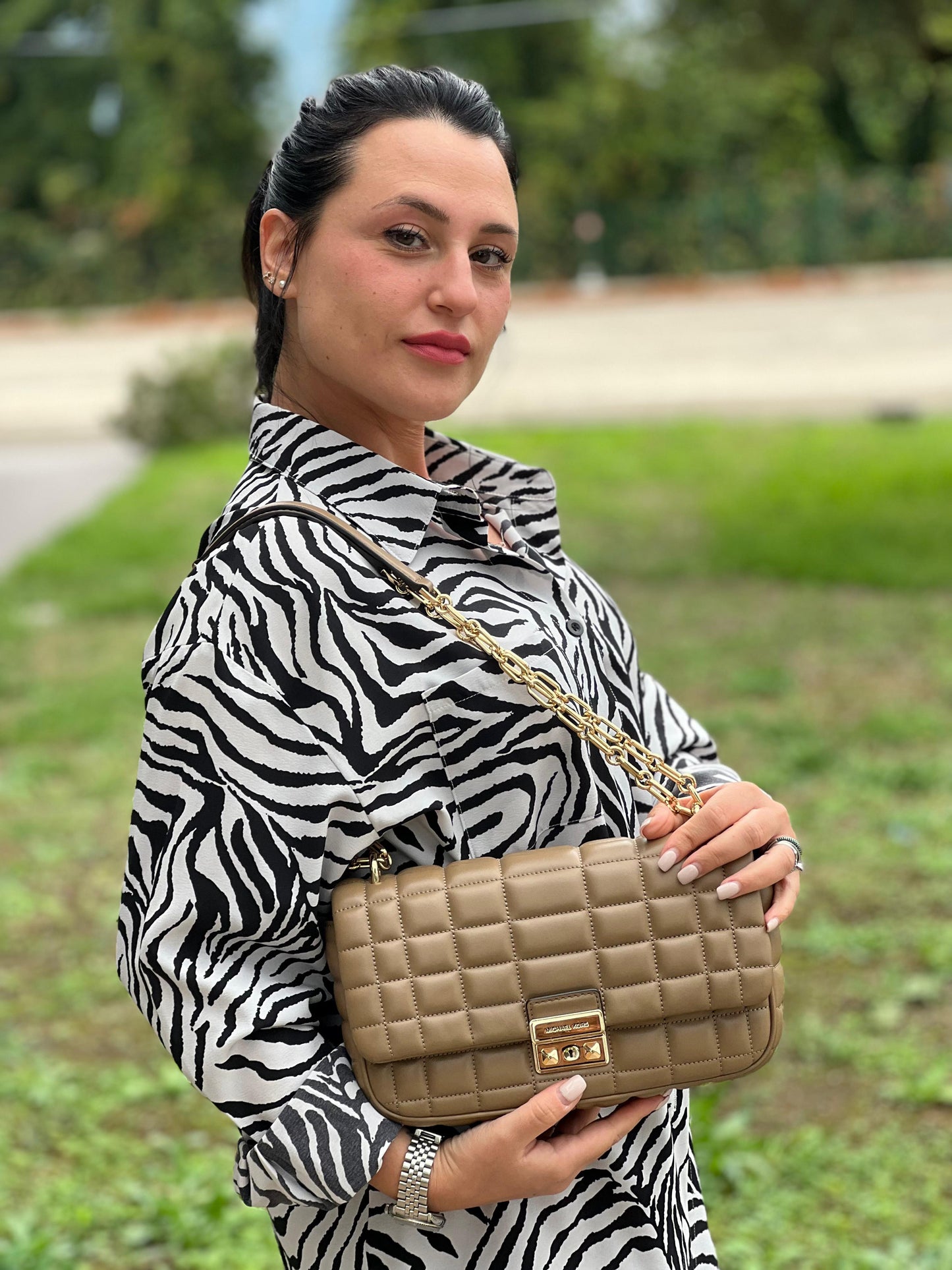 Foto indossata Borsa Michael Kors Tribeca in pelle matelassé écru con parti metalliche dorate. Munita di una tracolla scorrevole in catena con spallacci in pelle. Completa di dustbag. Originale, usato, in condizioni ottime. 