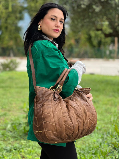 indossata della Borsa Miu Miu in pelle color cammello con parti metalliche dorate; munita di un manico singolo e una tracolla amovibile, di lusso, usata, originale, ottime condizioni. 