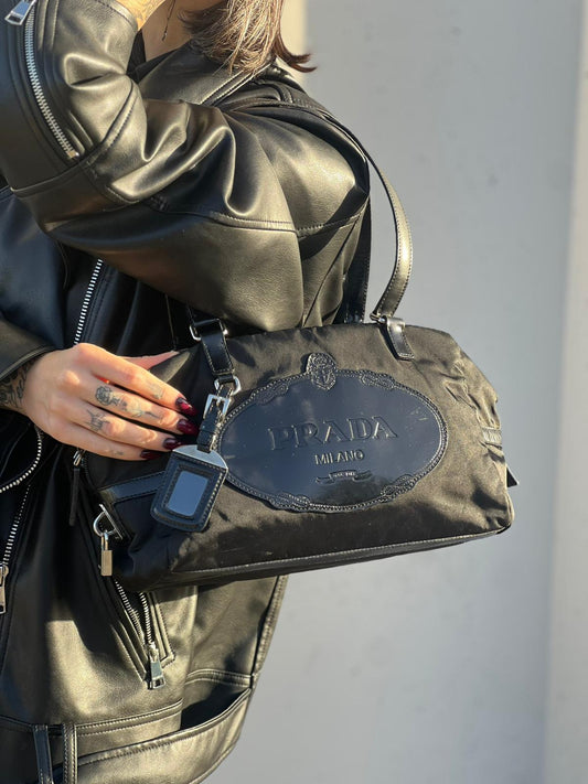 front Borsa Prada in nylon nero con finiture in pelle tono su tono e parti metalliche argentate; munita di doppi manici e accessorio porta address, di lusso, originale, ottime condizioni, usata. 