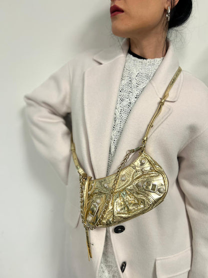 indossata Borsa Balenciaga in pelle dorata con parti metalliche dorate, impreziosita da borchie con cristalli incastonati; munita di un manico in catena e una tracolla regolabile. Completa di dustbag, di lusso, originale, ottime condizioni. 