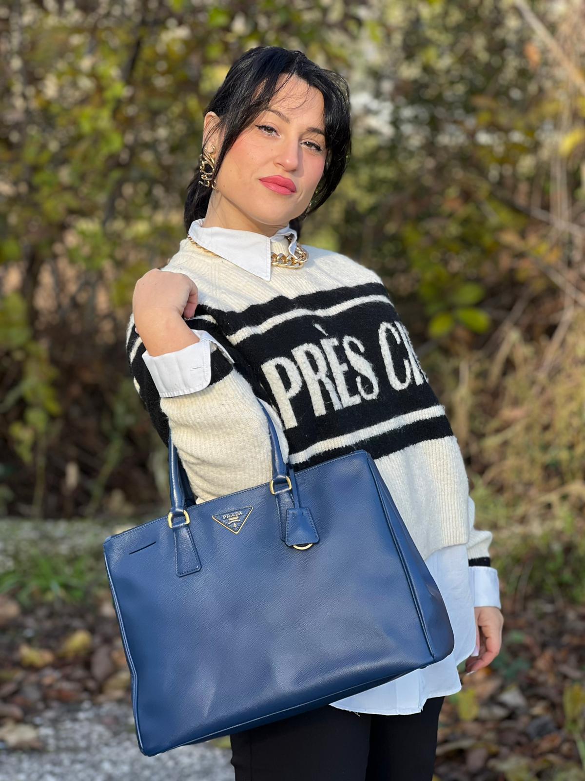 indossata Borsa Prada in pelle saffiano blu con parti metalliche dorate; munita di doppi manici stondati e impreziosita da una clochette portachiavi, di lusso, originale, ottime condizioni.