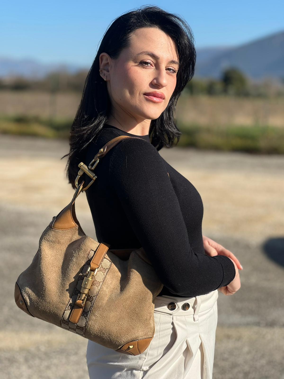 indossata della Borsa Gucci scamosciata beige con finiture in pelle color cammello, dettagli in tessuto GG e parti metalliche dorate; munita di un manico singolo, indossabile a spalla. Completa di dustbag, di lusso, originale, ottime condizioni, usata. 