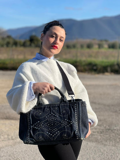 indossata Borsa Prada in denim blu rifinita con borchie metalliche argentate; munita di una tracolla in tessuto regolabile e amovibile e doppi manici; indossabile a mano o a tracolla. Completa di dustbag, di lusso, originale, buone condizioni. 