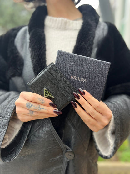 Portacarte Prada nera con parti metalliche argentate; impreziosito da iconico logo sul front. Completa di scatola, di lusso, originale, ottime condizioni, usato.