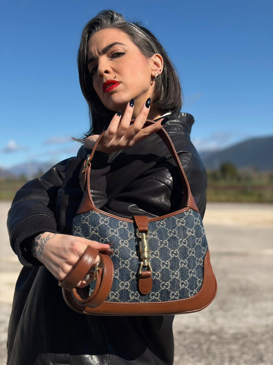 indossata  Borsa Gucci in tessuto blu GG denim, finiture in pelle marrone e parti metalliche dorate; munita di un manico singolo allungabile, indossabile a spalla o a tracolla, di lusso, originale, ottime condizioni, usata. 