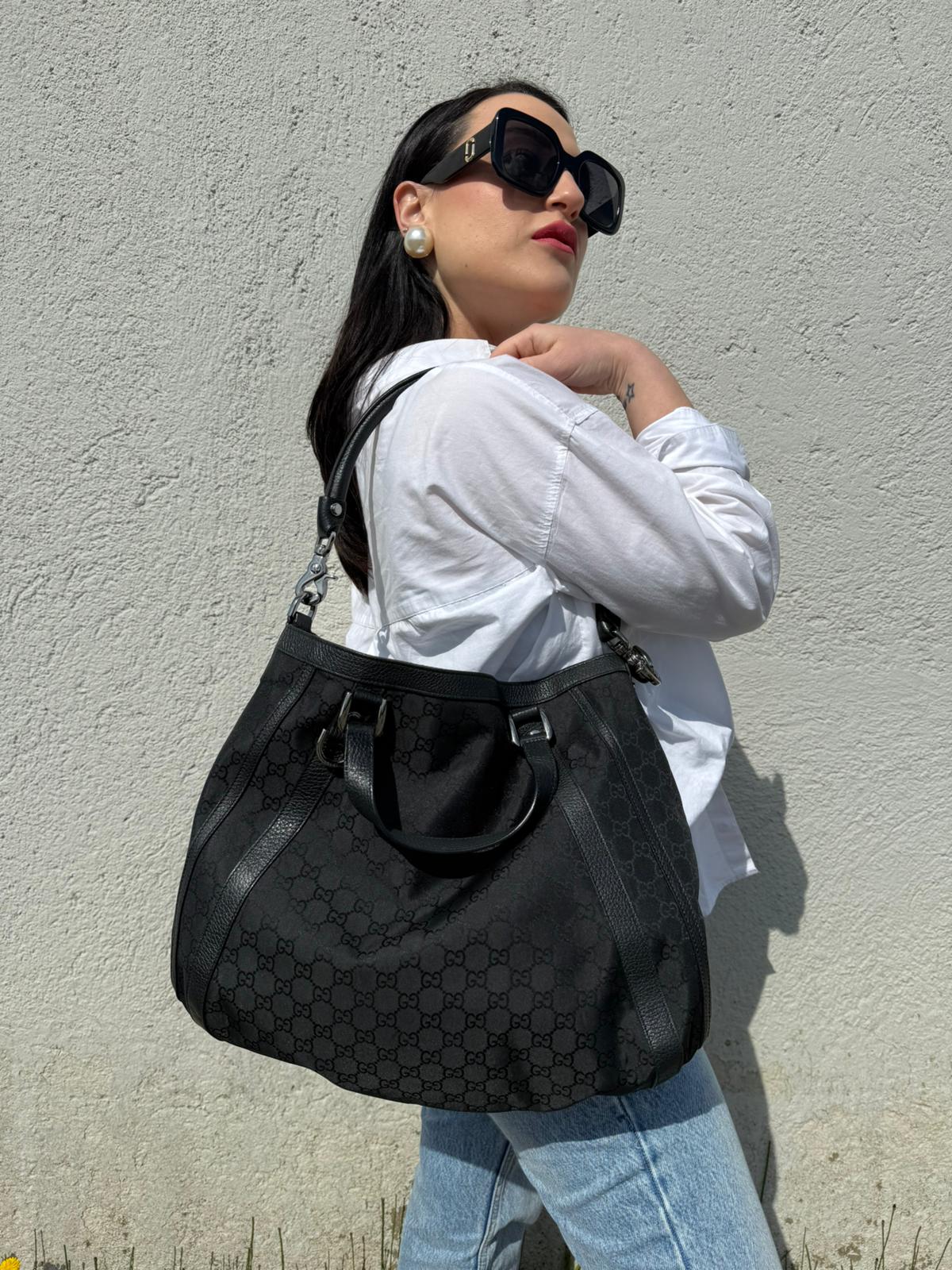 Indossata, Borsa Gucci in tessuto nero trama GG, con parti metalliche argentate, indossabile a mano o a spalla. Originale, usata, di lusso, in ottime condizioni.