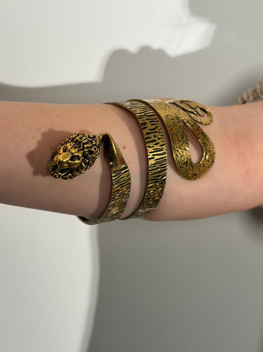 Indossata, Bracciale Gucci in metallo dorato invecchiato, caratterizzato da un design a spirale che termina con una testa di leone. Originale, usato, di lusso, in ottime condizioni.