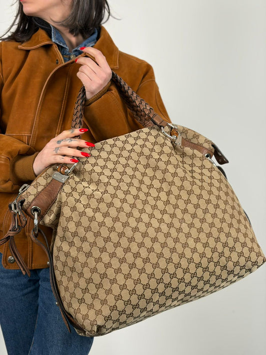 Indossata, Borsa Gucci in tessuto GG beige, munita di manici in pelle intrecciata e i caratteristici inserti in bamboo sugli attacchi dei manici. Originale, usata, di lusso, in ottime condizioni.
