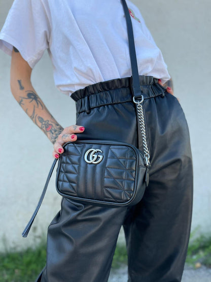 Indossata, Mini bag Gucci Marmont in pelle nera nella misura piccola, con hardware argentato, indossabile a tracolla. Originale, usata, di lusso, in ottime condizioni.