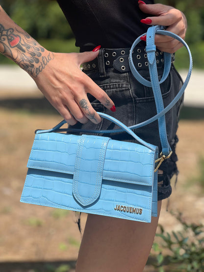 Borsa Jacquemus in pelle azzurra trama cocco con parti metalliche dorate; munita di un manico singolo e una tracolla amovibile e regolabile, indossata 
