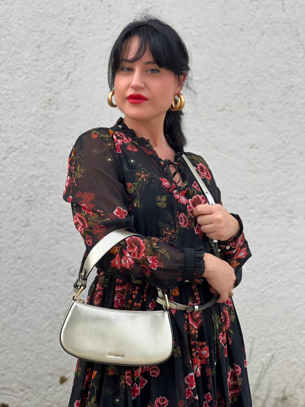 Ragazza chi indossa borsa Coccinelle in pelle color champagne munita di un manico singolo, una tracolla regolabile e amovibile con parti metalliche dorate. 