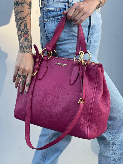 indossata Borsa Miu Miu in pelle martellata color rosa orchidea con parti metalliche dorate; munita di doppi manici e una tracolla tracolla amovibile e regolabile. Completa di dustbag, di lusso, originale, ottime condizioni. 